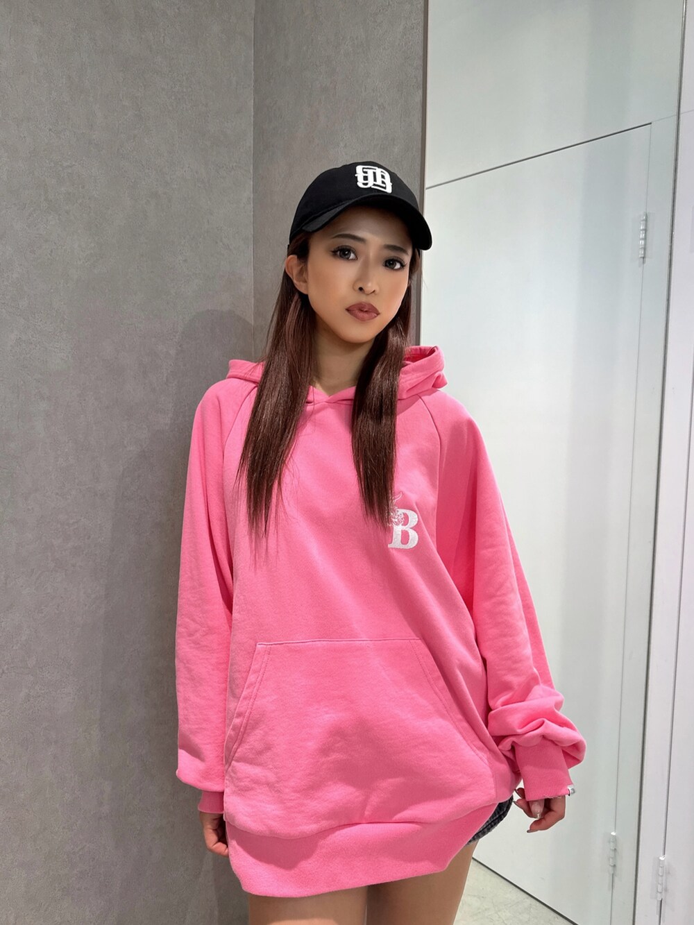 ピンク系のパーカー、ブラック系のショルダーバッグ、ブラック系のブーツを着用したレディースの冬コーディネートの2枚目の写真