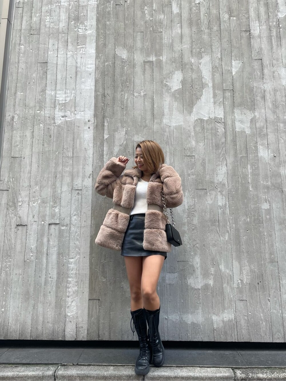 ブラック系のブーツ、ベージュ系のその他アウター、ホワイト系のニット/セーターを着用したレディースの冬コーディネートの2枚目の写真