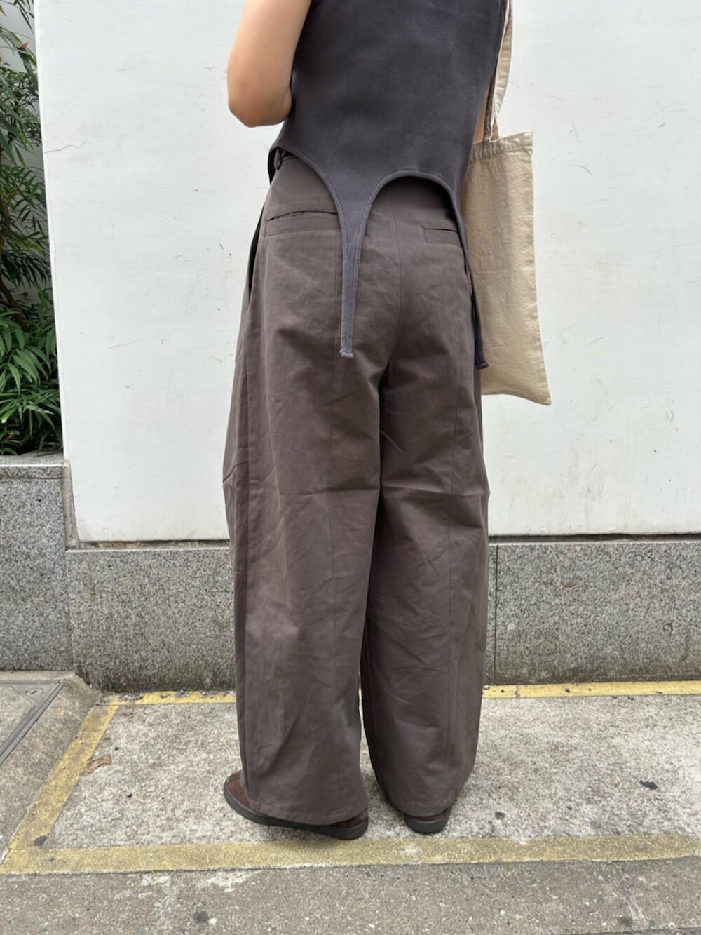 グレー系のチノパンツ、グレー系のタンクトップ、ホワイト系のトートバッグを着用したレディースの春コーディネートの6枚目の写真