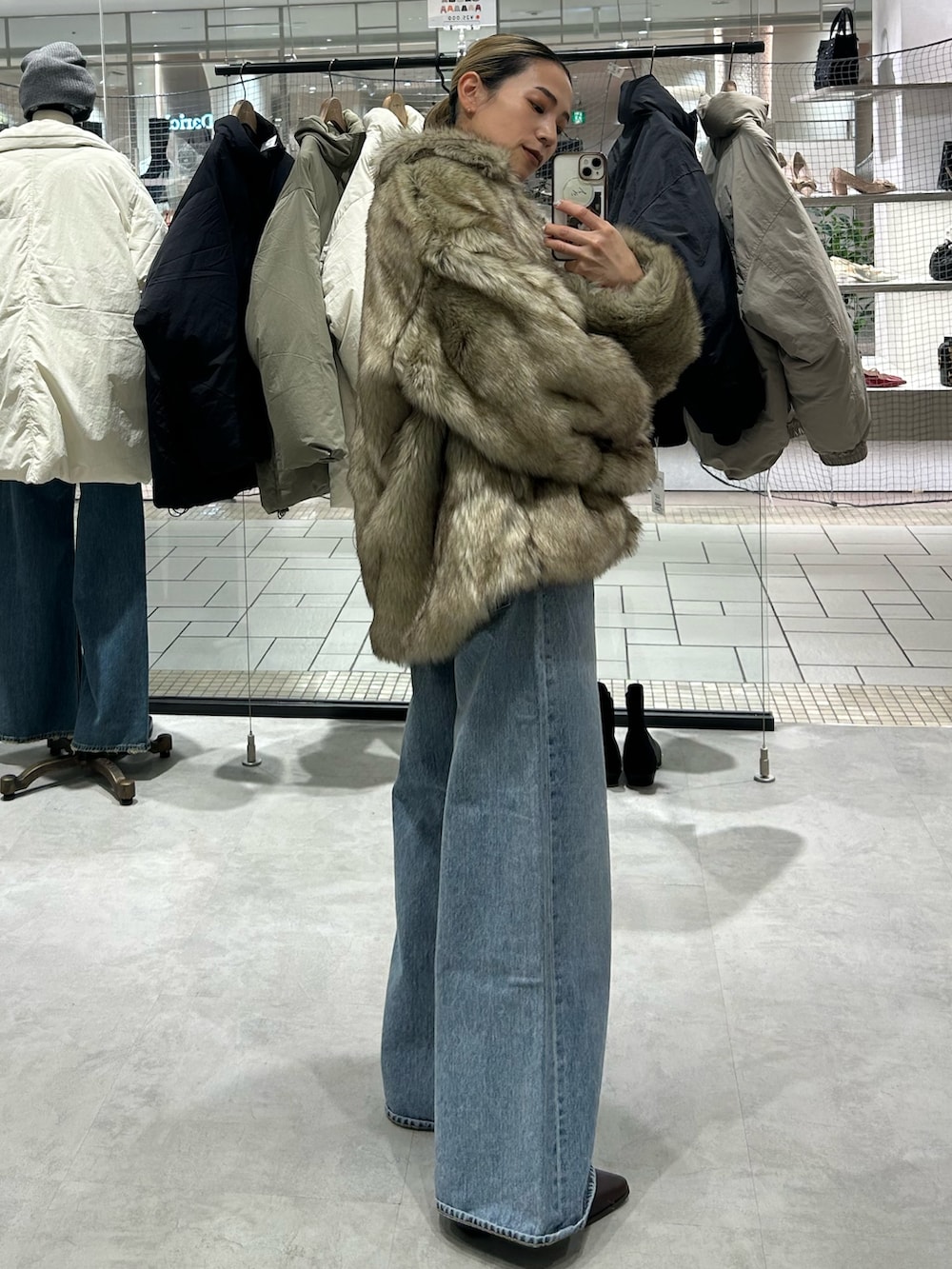 ベージュ系のダウンジャケット/コート、レッド系のニット/セーター、ブルー系のデニムパンツを着用したレディースの冬コーディネートの2枚目の写真