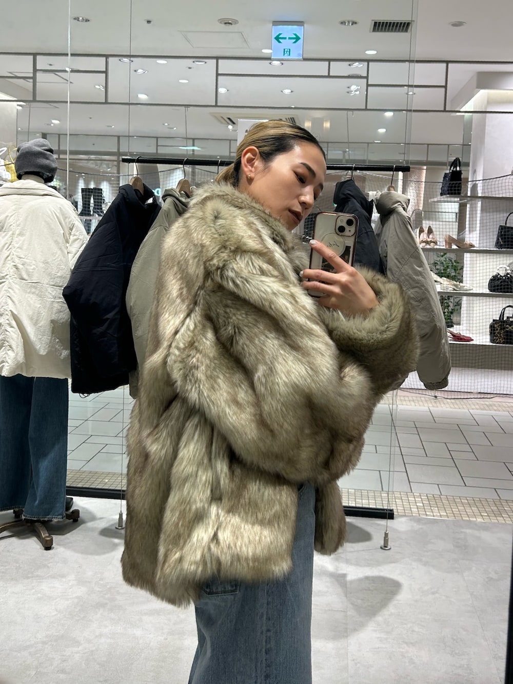 ベージュ系のダウンジャケット/コート、レッド系のニット/セーター、ブルー系のデニムパンツを着用したレディースの冬コーディネートの5枚目の写真