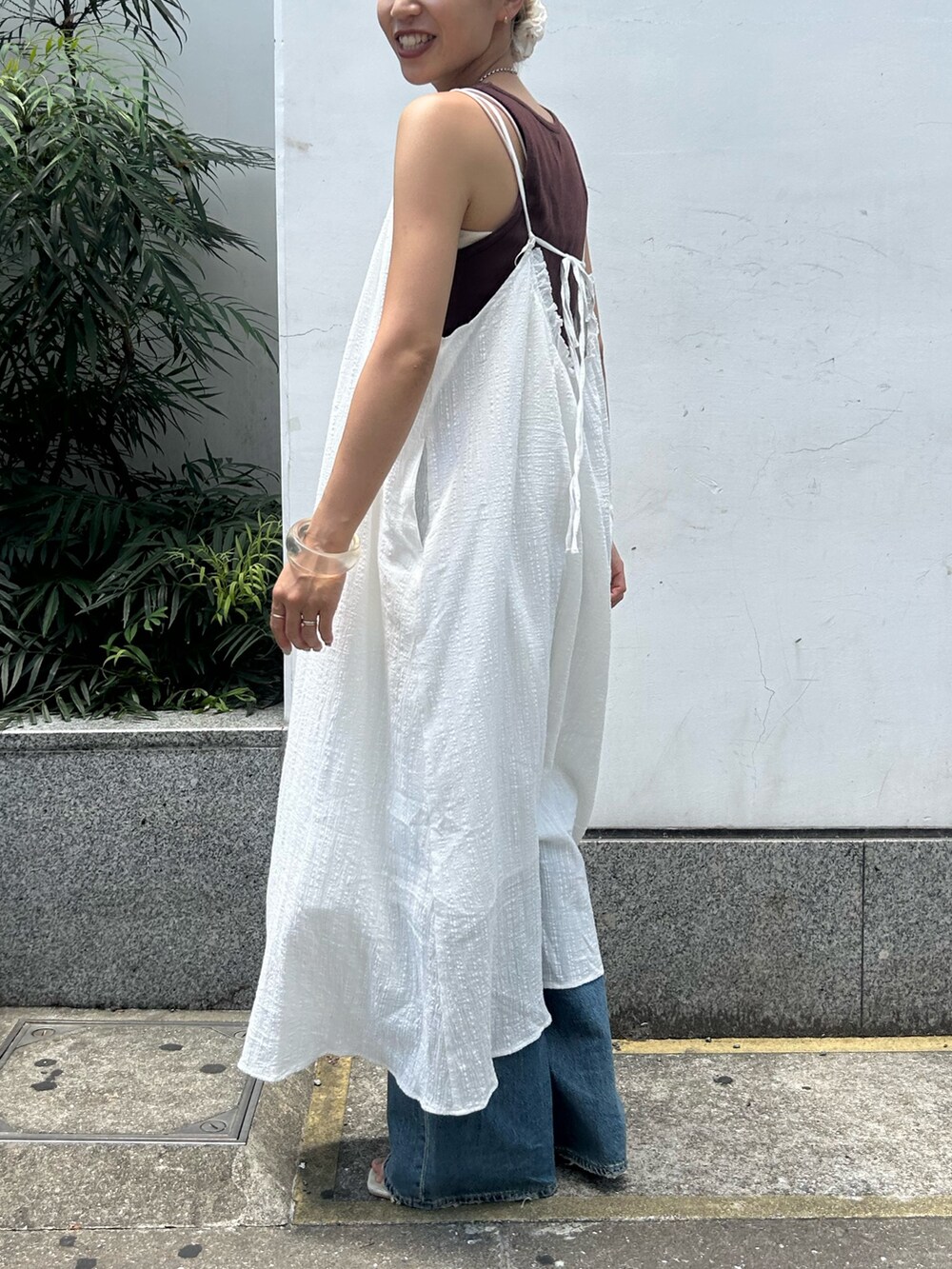 ホワイト系のワンピース、ブラウン系のタンクトップ、ブルー系のデニムパンツを着用したレディースの夏コーディネートの2枚目の写真