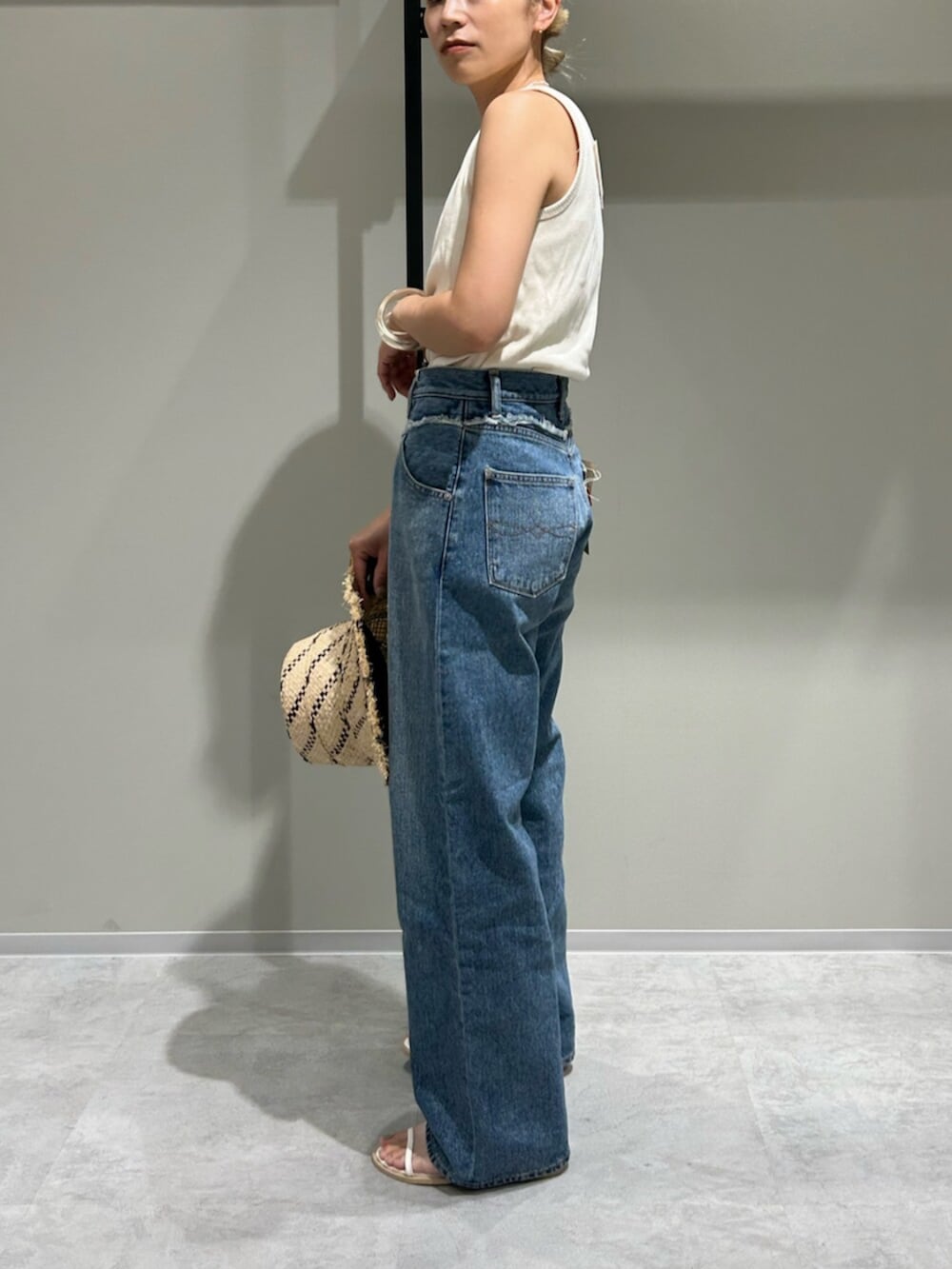 ホワイト系のサンダル、ブルー系のデニムパンツ、ホワイト系のタンクトップを着用したレディースの夏コーディネートの2枚目の写真