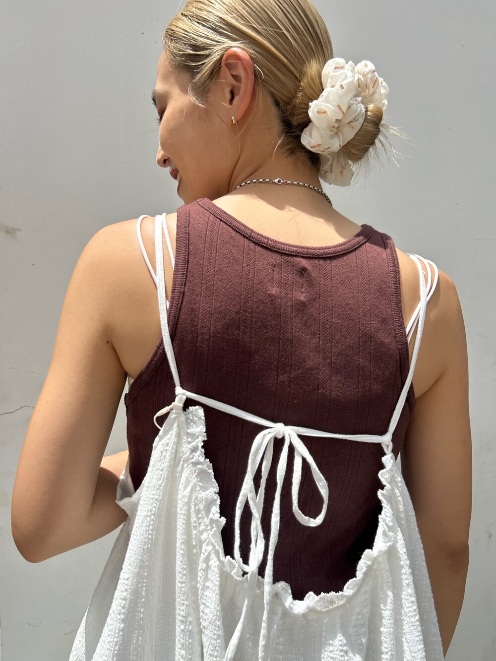 ホワイト系のワンピース、ブラウン系のタンクトップ、ブルー系のデニムパンツを着用したレディースの夏コーディネートの6枚目の写真