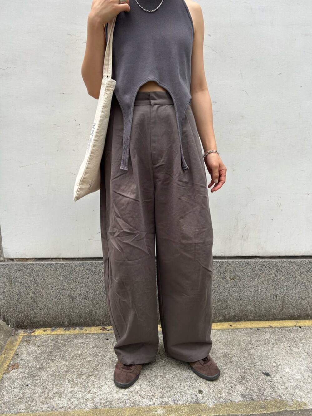 グレー系のチノパンツ、グレー系のタンクトップ、ホワイト系のトートバッグを着用したレディースの春コーディネートの4枚目の写真