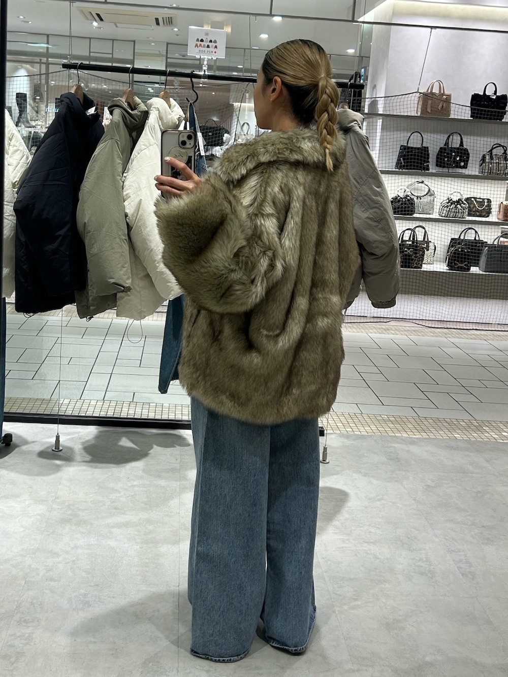 ベージュ系のダウンジャケット/コート、レッド系のニット/セーター、ブルー系のデニムパンツを着用したレディースの冬コーディネートの3枚目の写真