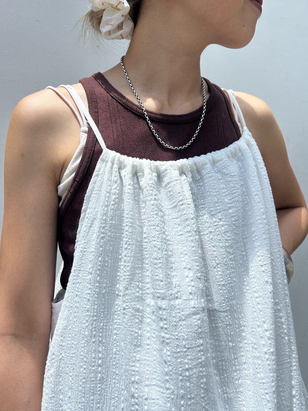 ホワイト系のワンピース、ブラウン系のタンクトップ、ブルー系のデニムパンツを着用したレディースの夏コーディネートの5枚目の写真