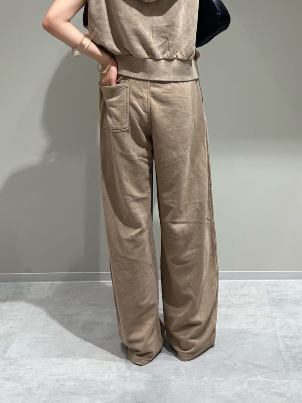 ブラック系のハンドバッグ、ベージュ系のパーカー、ベージュ系のスウェットパンツを着用したレディースの夏コーディネートの5枚目の写真