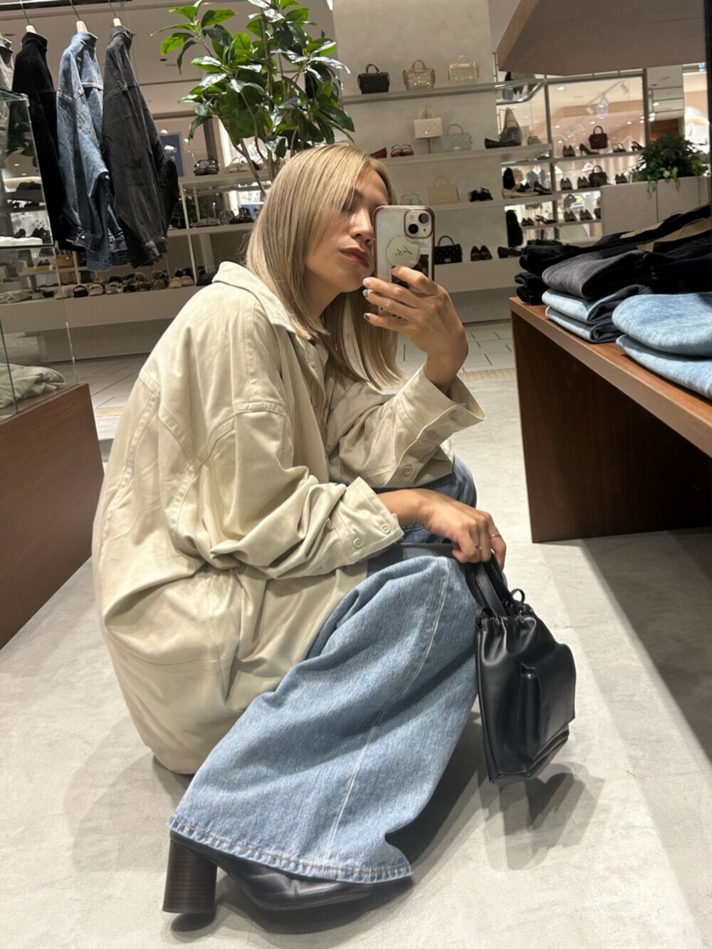 ブラック系のショルダーバッグ、ホワイト系のシャツ/ブラウス、ブルー系のデニムパンツを着用したレディースの秋コーディネートの5枚目の写真