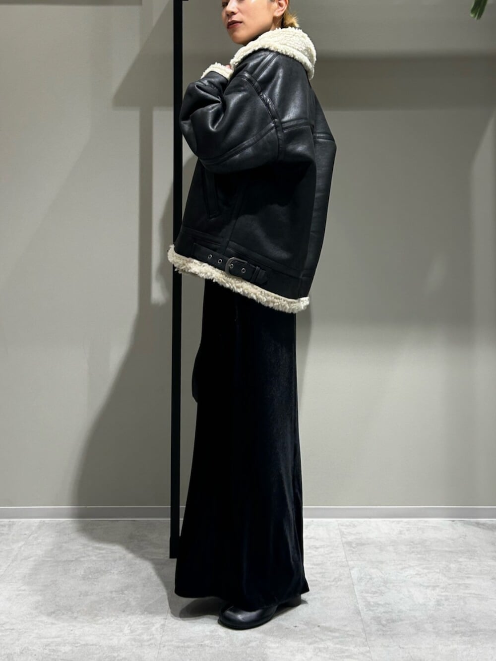 ブラック系のスカート、ブラック系のブルゾン、グレー系のキャミソールを着用したレディースの秋コーディネートの2枚目の写真