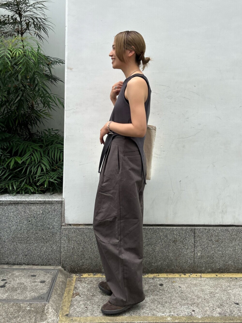 グレー系のチノパンツ、グレー系のタンクトップ、ホワイト系のトートバッグを着用したレディースの春コーディネートの2枚目の写真