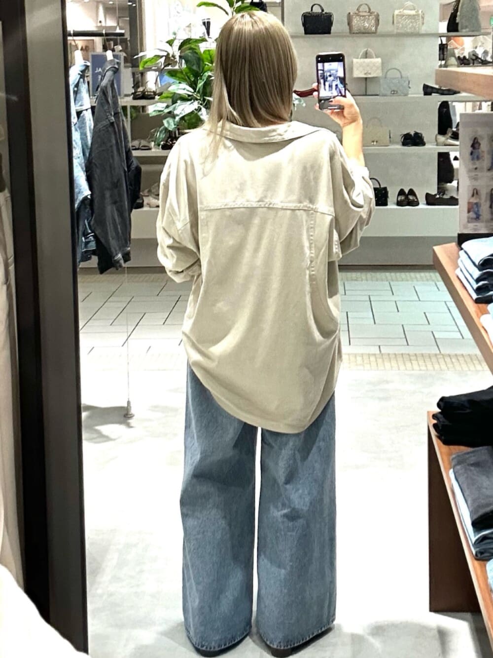 ブラック系のショルダーバッグ、ホワイト系のシャツ/ブラウス、ブルー系のデニムパンツを着用したレディースの秋コーディネートの3枚目の写真