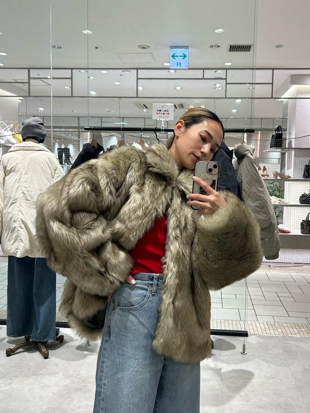 ベージュ系のダウンジャケット/コート、レッド系のニット/セーター、ブルー系のデニムパンツを着用したレディースの冬コーディネートの4枚目の写真