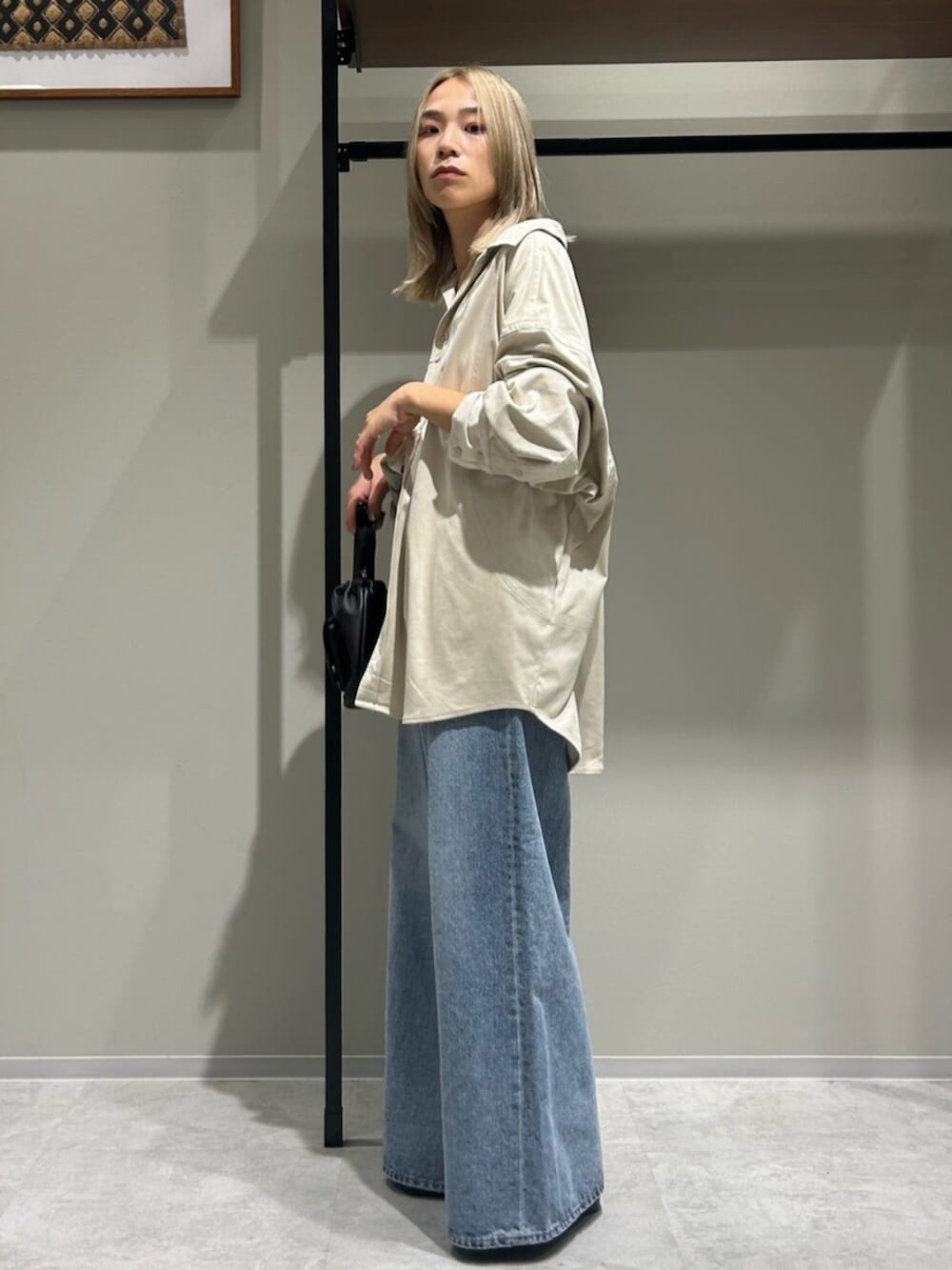 ブラック系のショルダーバッグ、ホワイト系のシャツ/ブラウス、ブルー系のデニムパンツを着用したレディースの秋コーディネートの2枚目の写真