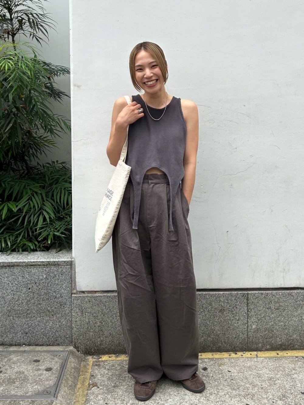 グレー系のチノパンツ、グレー系のタンクトップ、ホワイト系のトートバッグを着用したレディースの春コーディネートの7枚目の写真