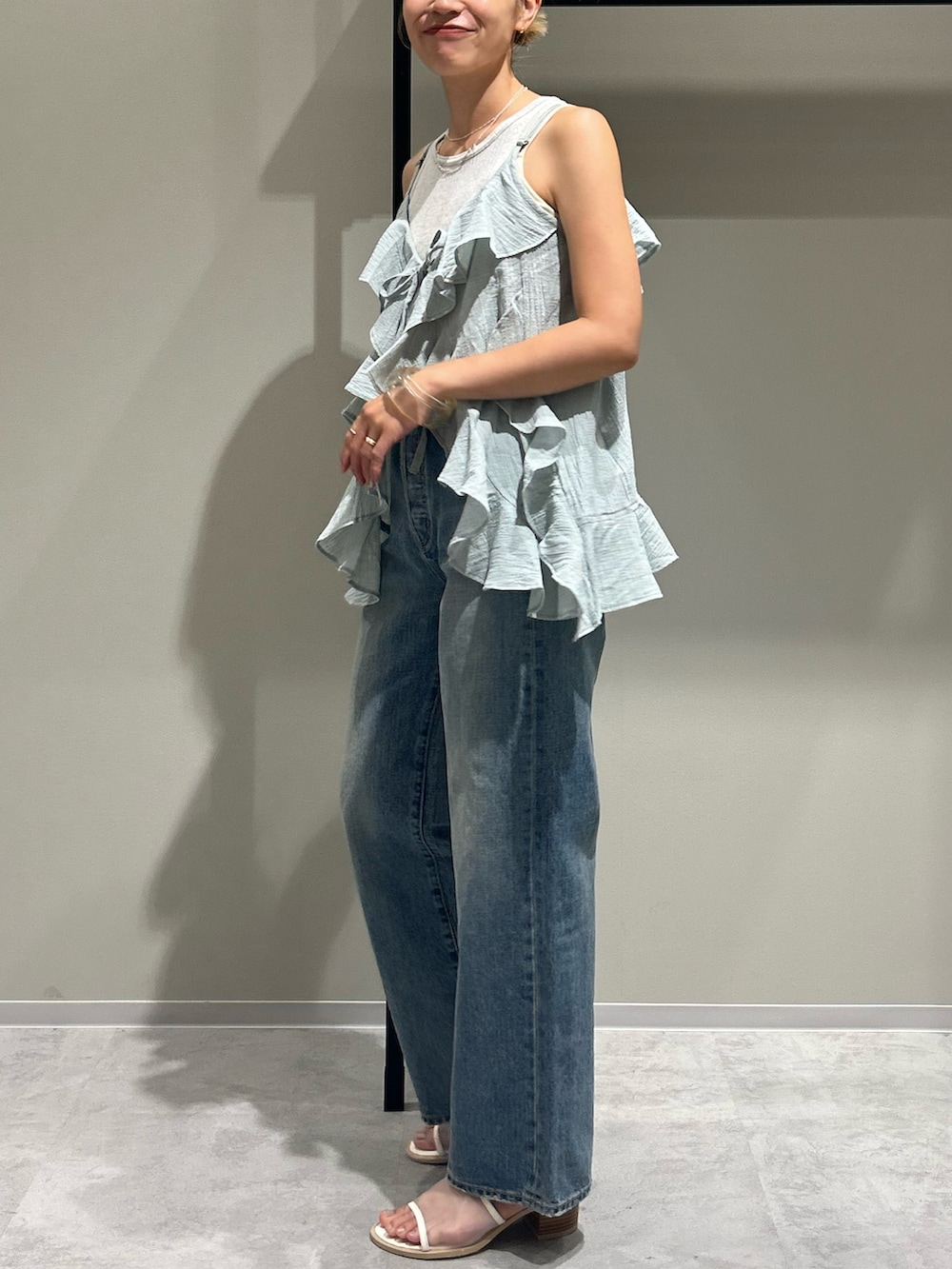 ブルー系のデニムパンツ、グリーン系のキャミソール、グレー系のタンクトップを着用したレディースの夏コーディネートの2枚目の写真