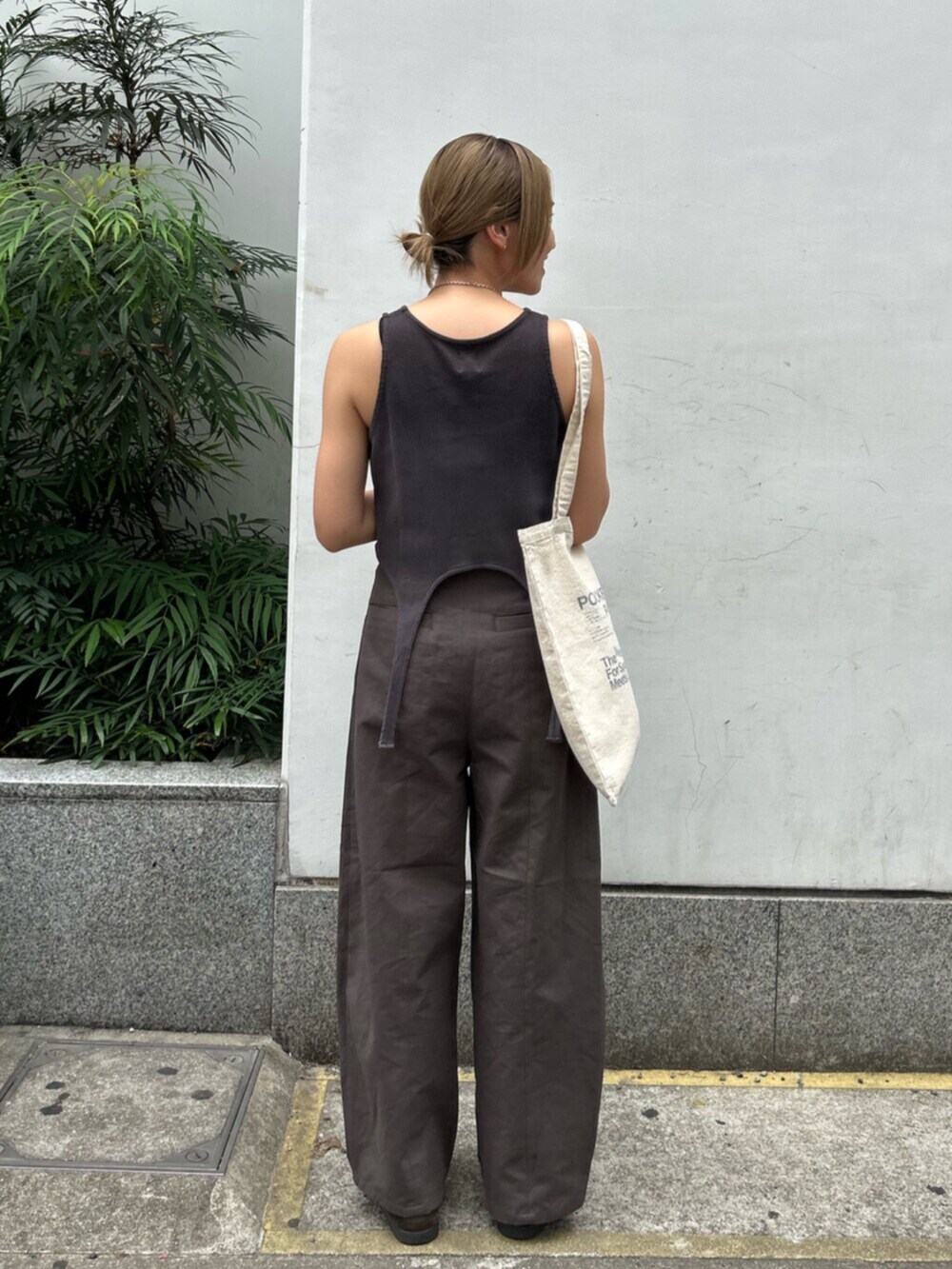 グレー系のチノパンツ、グレー系のタンクトップ、ホワイト系のトートバッグを着用したレディースの春コーディネートの3枚目の写真