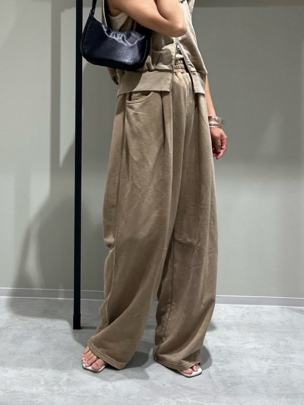 ブラック系のハンドバッグ、ベージュ系のパーカー、ベージュ系のスウェットパンツを着用したレディースの夏コーディネートの4枚目の写真