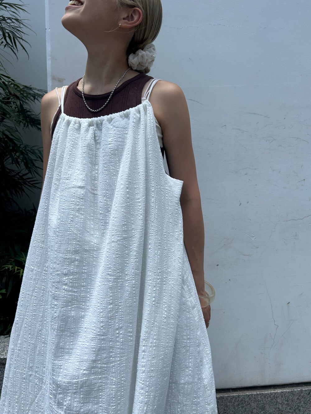 ホワイト系のワンピース、ブラウン系のタンクトップ、ブルー系のデニムパンツを着用したレディースの夏コーディネートの4枚目の写真