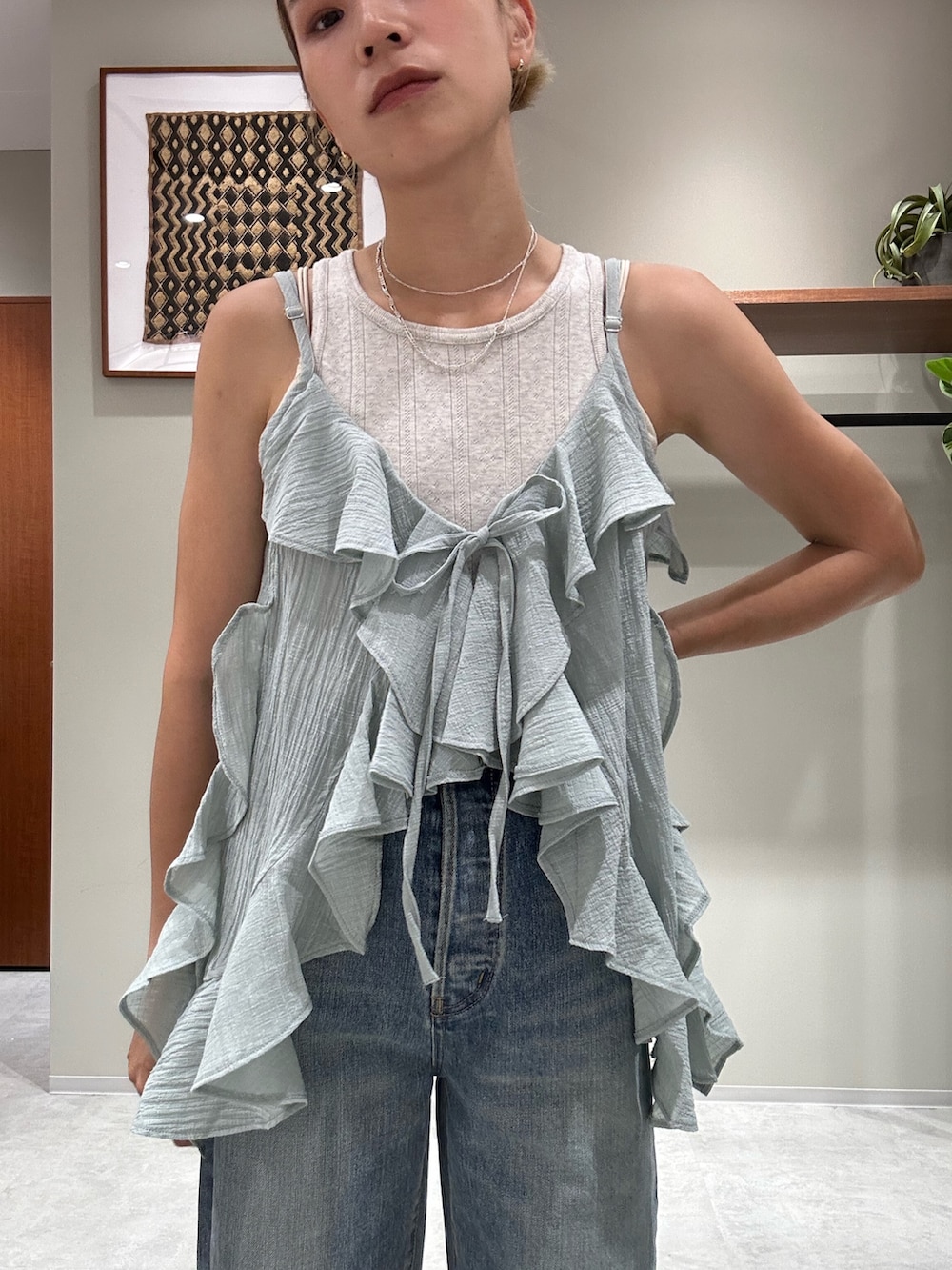 ブルー系のデニムパンツ、グリーン系のキャミソール、グレー系のタンクトップを着用したレディースの夏コーディネートの4枚目の写真