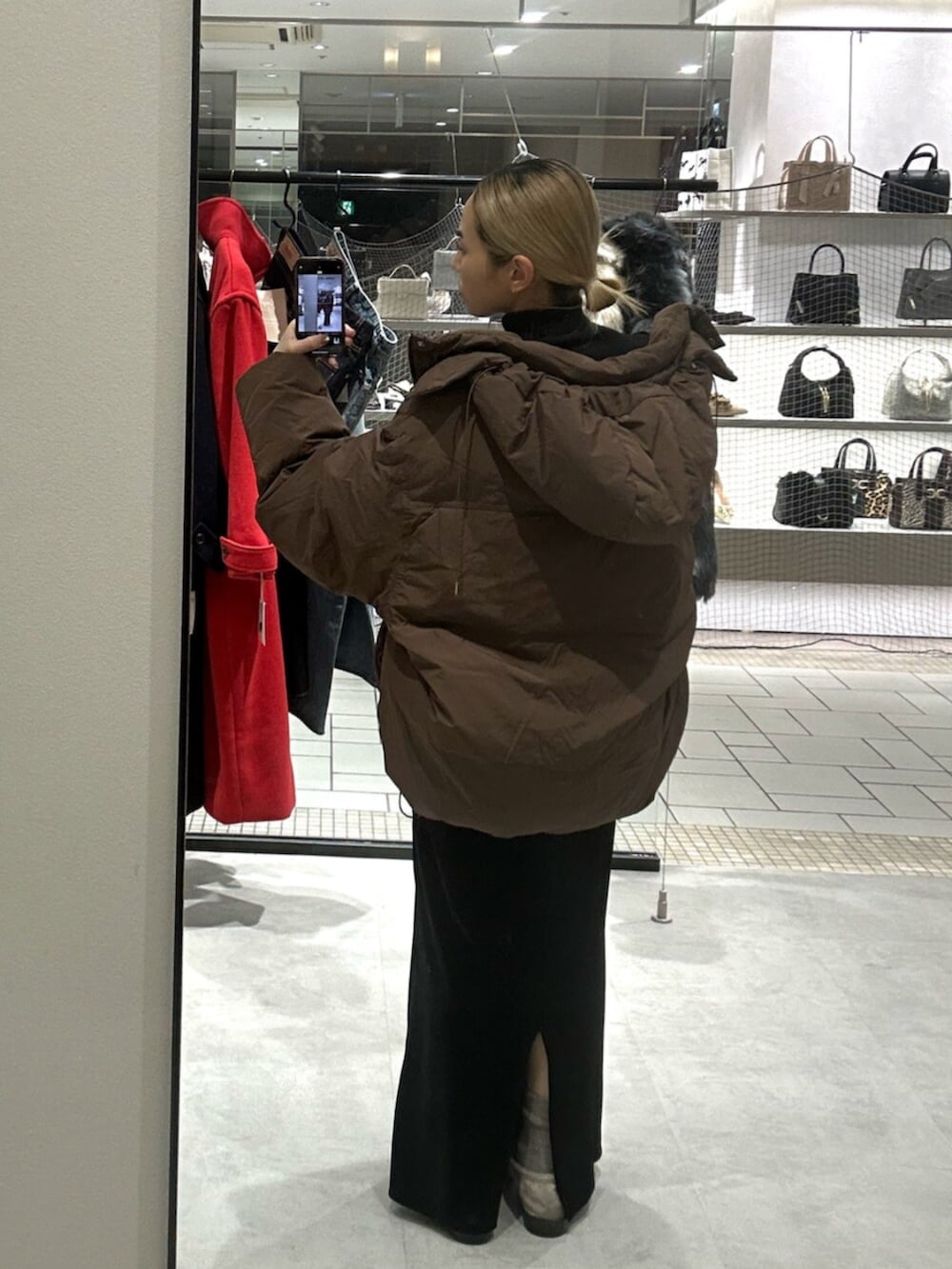 ブラック系のスカート、ベージュ系のローファー、ブラウン系のダウンジャケット/コートを着用したレディースの秋コーディネートの3枚目の写真