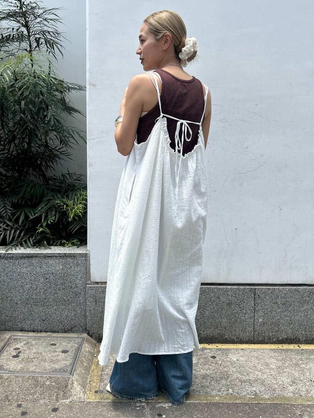 ホワイト系のワンピース、ブラウン系のタンクトップ、ブルー系のデニムパンツを着用したレディースの夏コーディネートの3枚目の写真