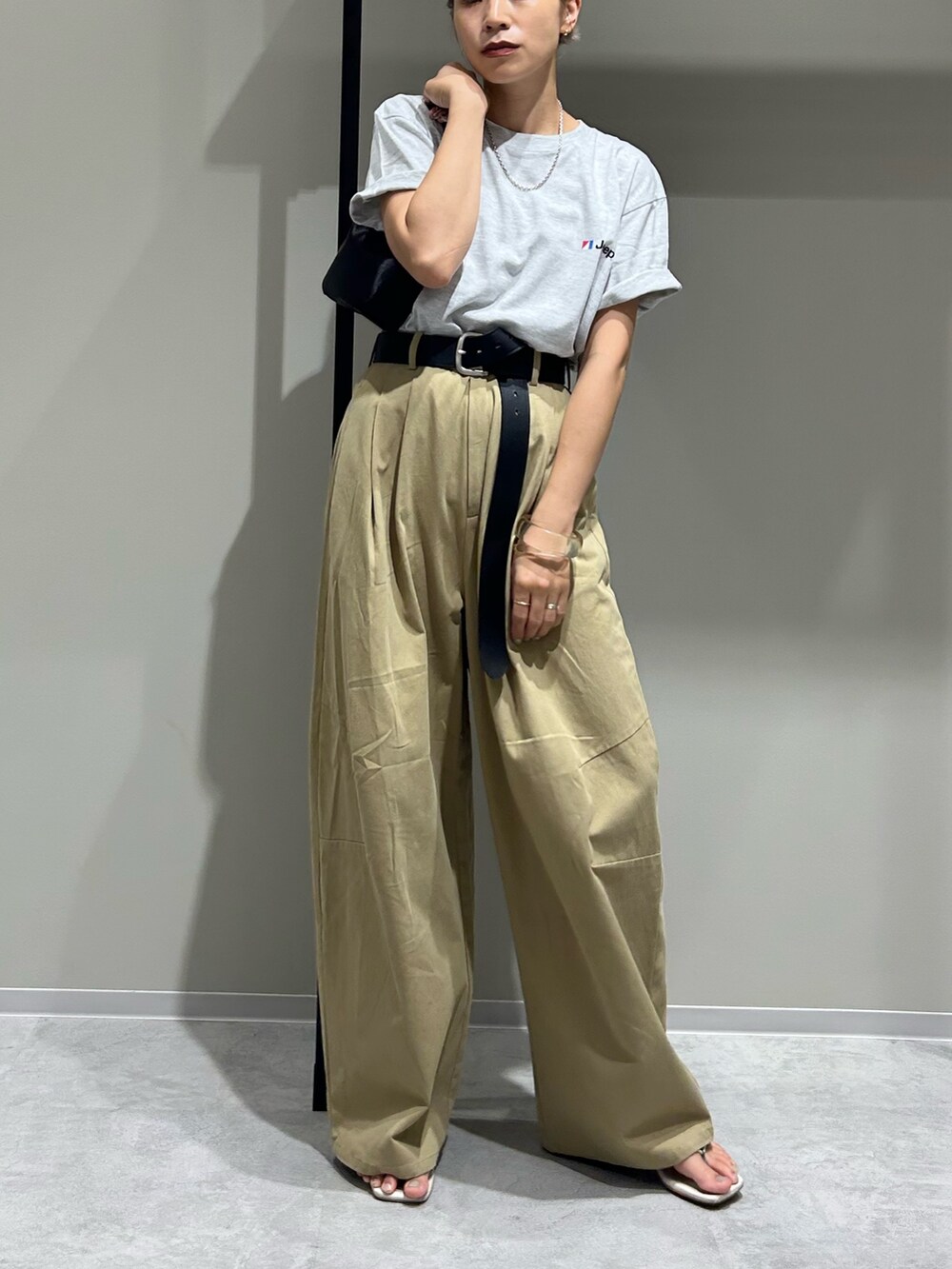 ベージュ系のチノパンツ、グレー系のTシャツ/カットソー、ブラック系のハンドバッグを着用したレディースの夏コーディネートの2枚目の写真