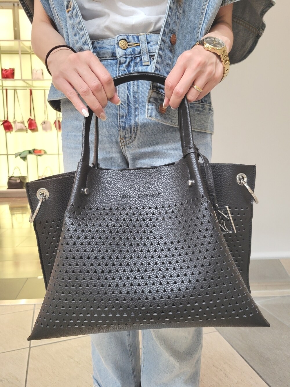 ブラック系のハンドバッグ、ホワイト系のサンダル、ブルー系のデニムジャケットを着用したレディースの夏コーディネートの2枚目の写真