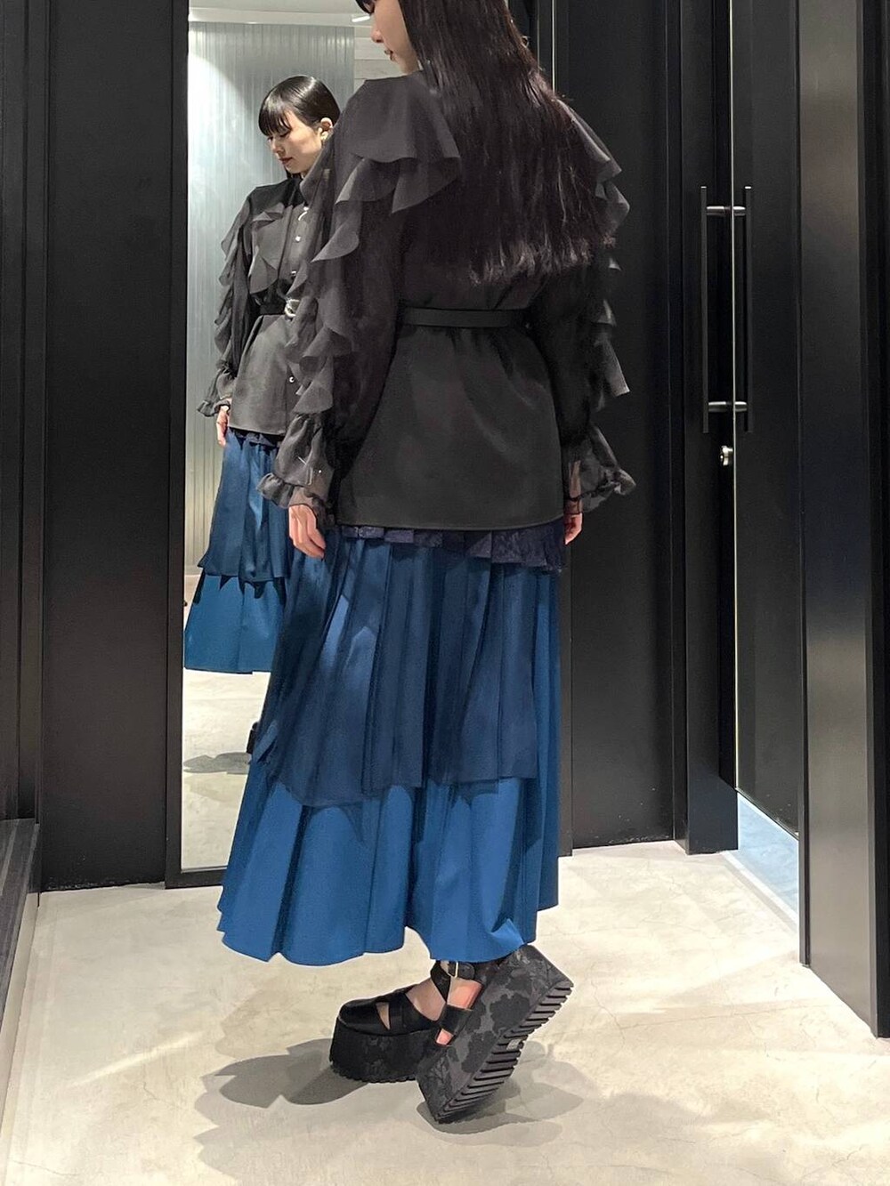 ブラック系のサンダル、ブラック系のシャツ/ブラウス、ブルー系のスカートを着用したレディースの春コーディネートの3枚目の写真