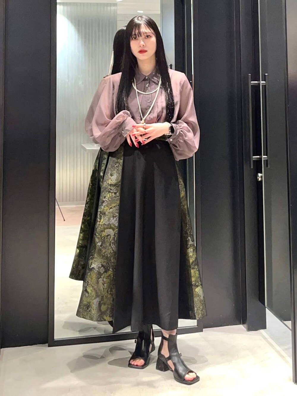 イエロー系のスカート、ブラック系のサンダル、ベージュ系のシャツ/ブラウスを着用したレディースの春コーディネートの2枚目の写真