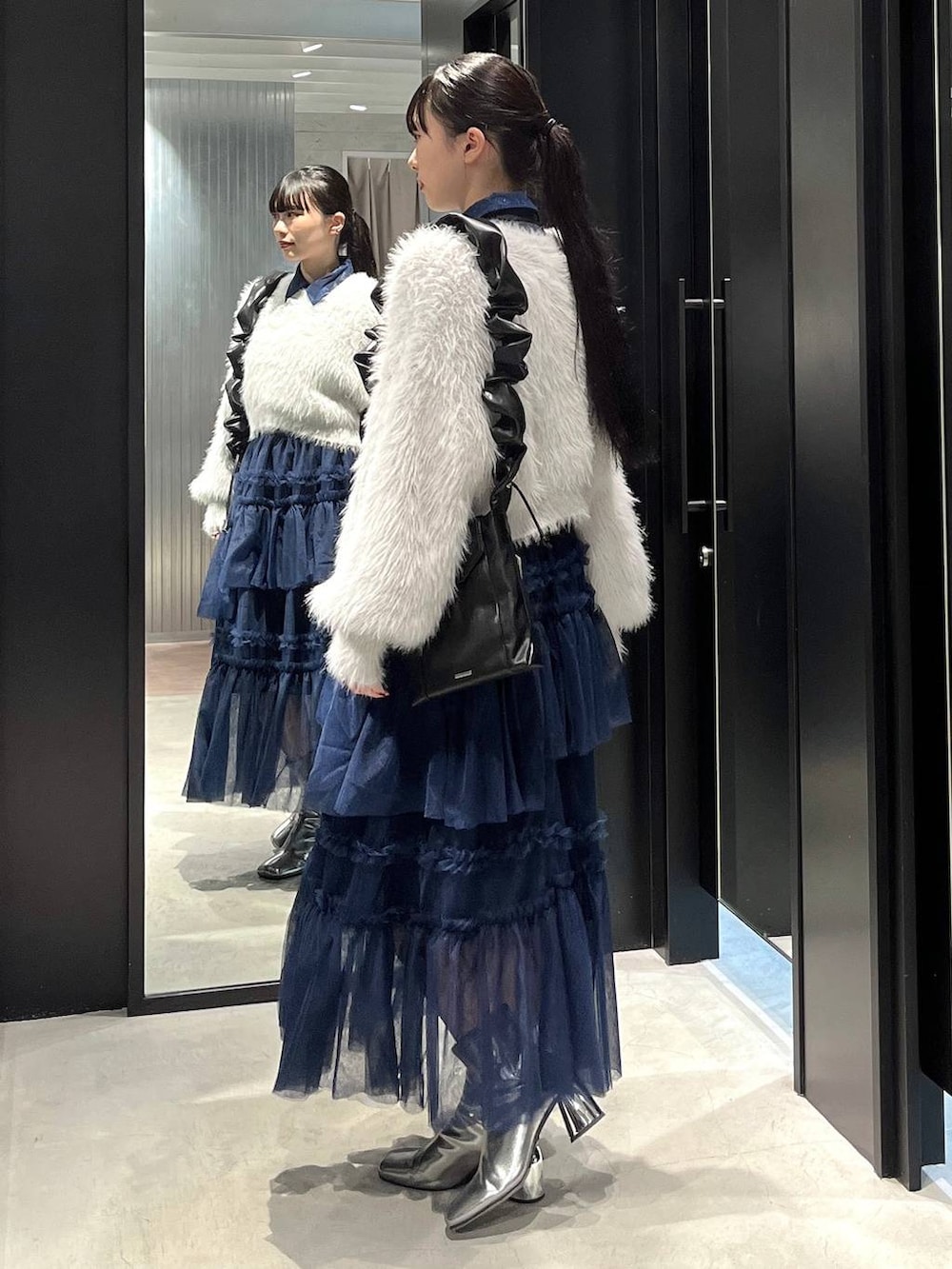 グレー系のニット/セーター、シルバー系のブーツ、ブルー系のシャツ/ブラウスを着用したレディースの秋コーディネートの3枚目の写真