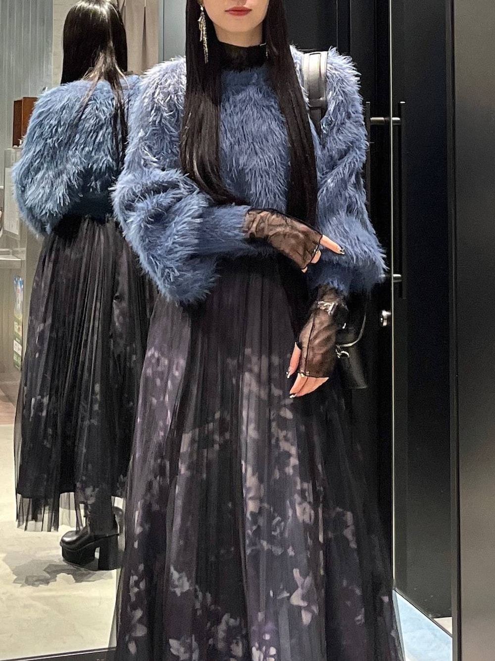 ブルー系のニット/セーター、ブラック系のブーツ、ブラック系のショルダーバッグを着用したレディースの秋コーディネートの3枚目の写真