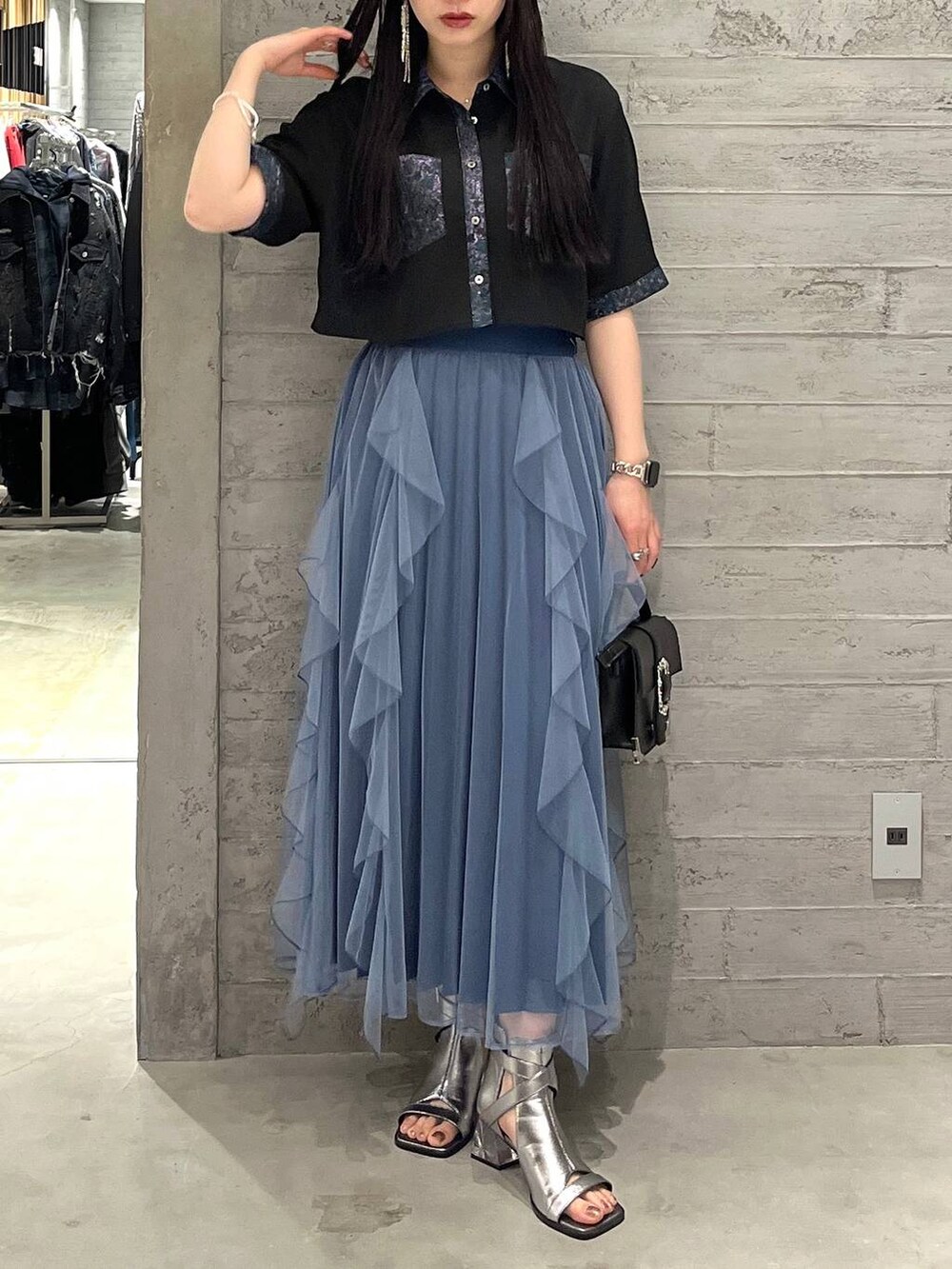 ブラック系のショルダーバッグ、ブルー系のスカート、シルバー系のサンダルを着用したレディースの春コーディネートの4枚目の写真