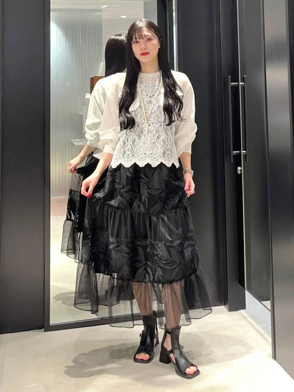 ホワイト系のTシャツ/カットソー、ブラック系のサンダル、ブラック系のスカートを着用したレディースの春コーディネートの2枚目の写真