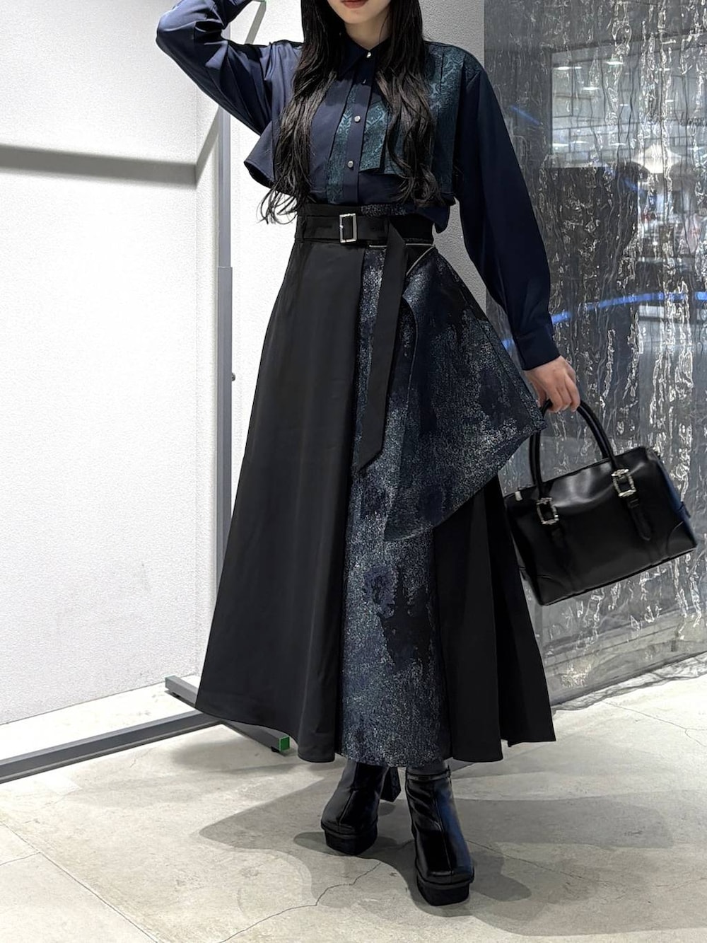 ブラック系のボストンバッグ、ブラック系のブーツ、グリーン系のスカートを着用したレディースの冬コーディネートの5枚目の写真