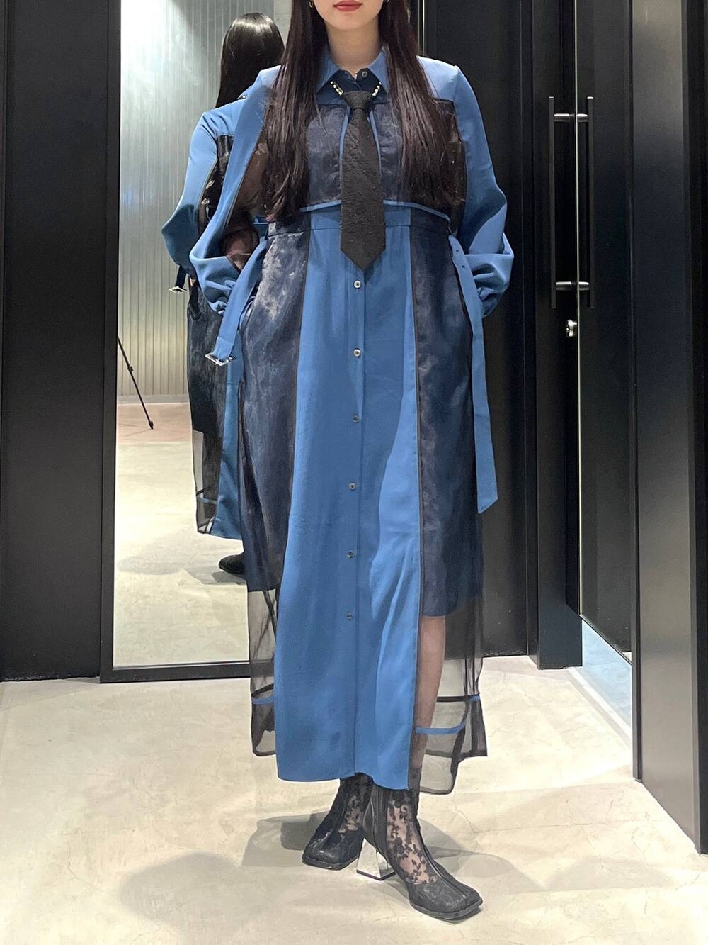 ブラック系のネクタイ、ブラック系のブーツ、ブルー系のワンピースを着用したレディースの春コーディネートの2枚目の写真