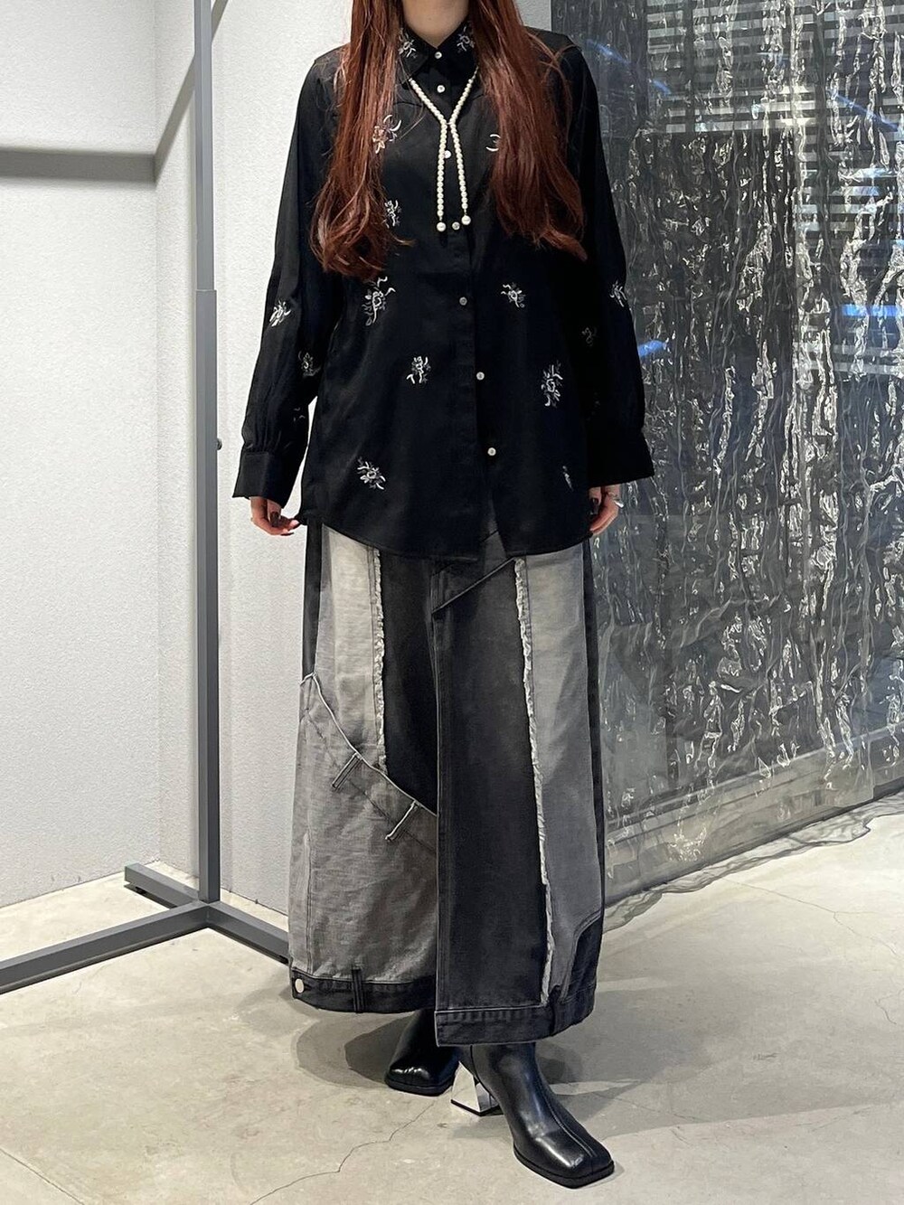 ブラック系のデニムスカート、ブラック系のシャツ/ブラウス、ブラック系のブーツを着用したレディースの秋コーディネートの3枚目の写真