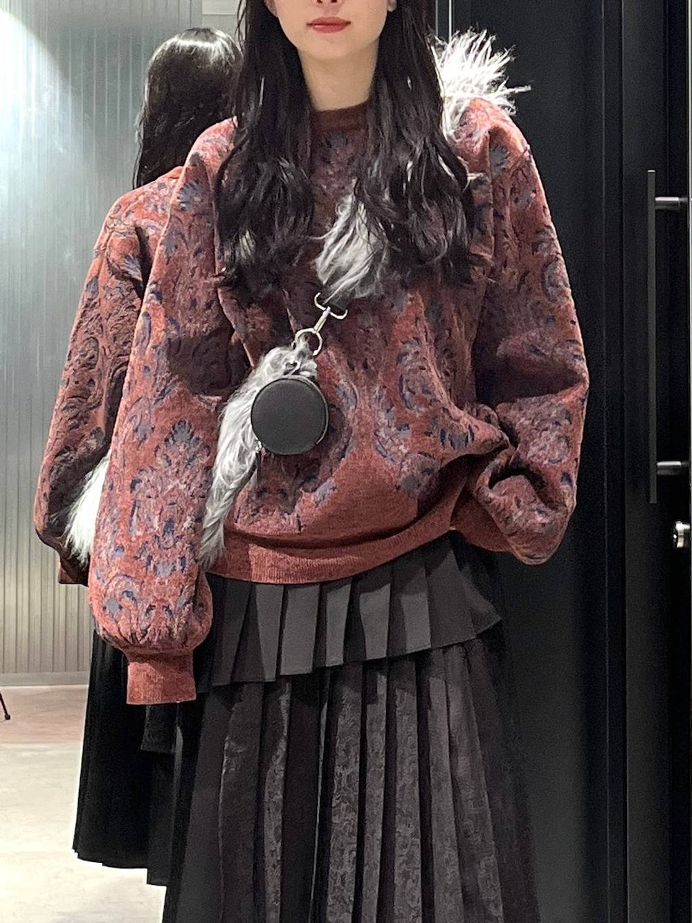 シルバー系のブーツ、レッド系のニット/セーター、ブラック系のスカートを着用したレディースの冬コーディネートの4枚目の写真