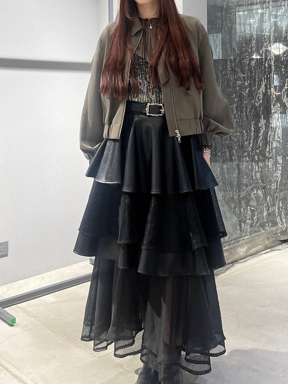 ブラック系のスカート、ベージュ系のブルゾン、ブラック系のブーツを着用したレディースの夏コーディネートの4枚目の写真