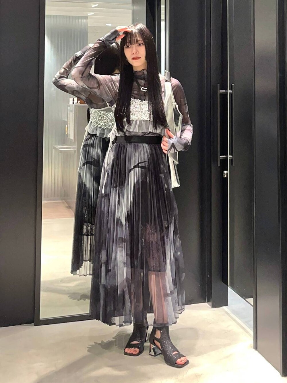 シルバー系のチューブトップ、ブラック系のサンダル、シルバー系のトートバッグを着用したレディースの春コーディネートの2枚目の写真