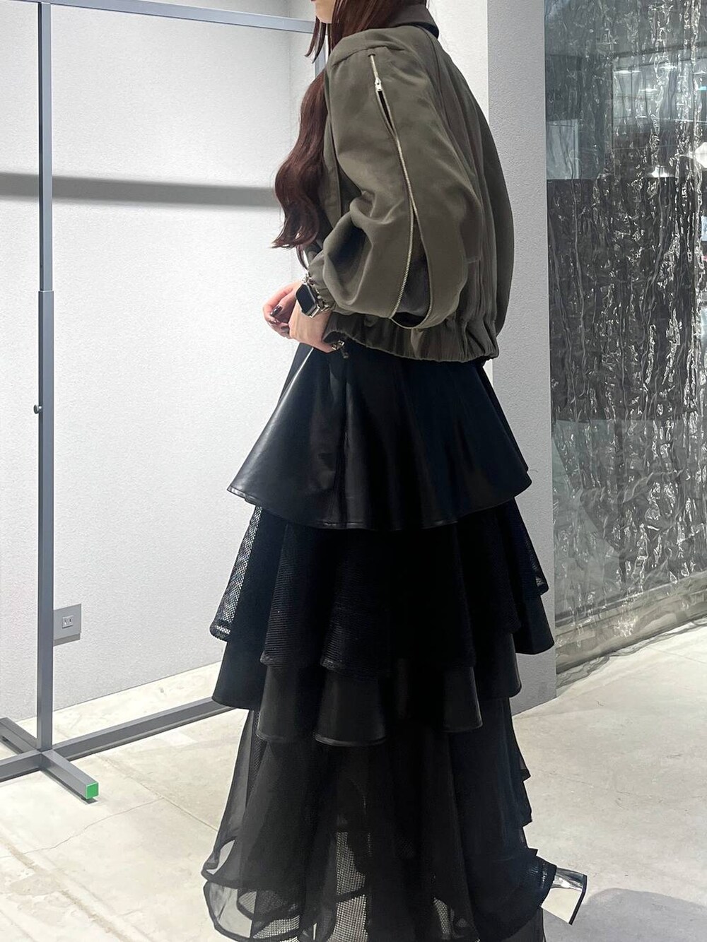 ブラック系のスカート、ベージュ系のブルゾン、ブラック系のブーツを着用したレディースの夏コーディネートの3枚目の写真