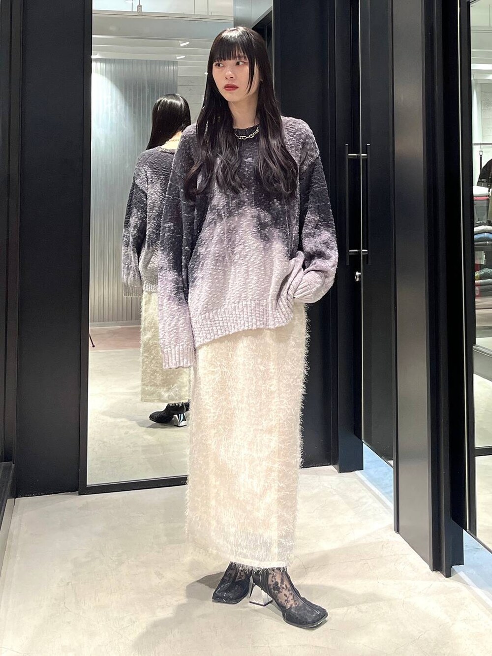 ブラック系のブーツ、ホワイト系のスカート、ブラック系のニット/セーターを着用したレディースの冬コーディネートの5枚目の写真