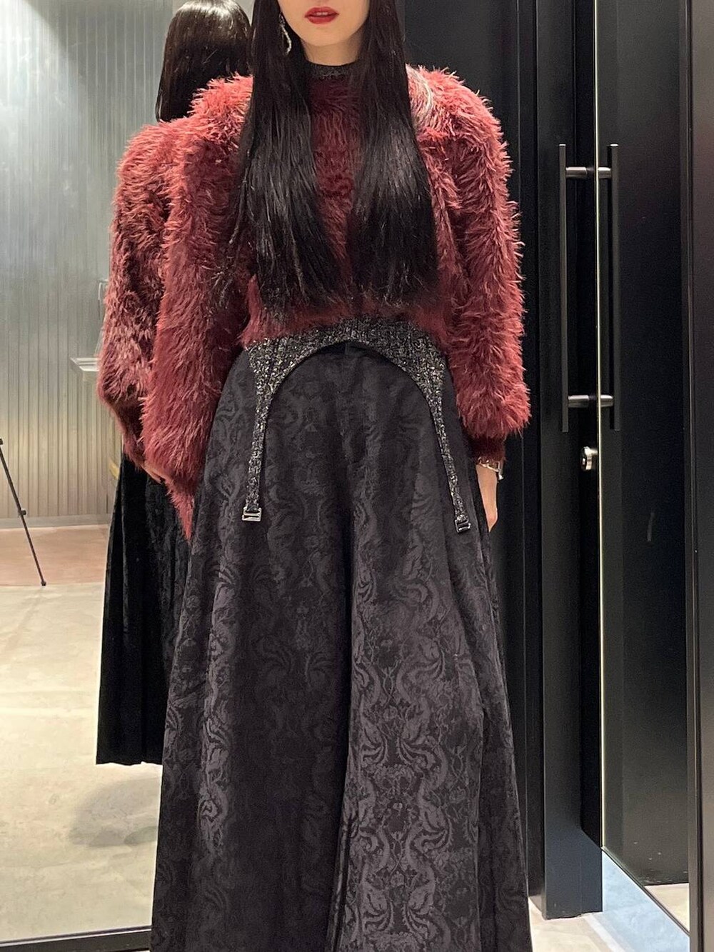 レッド系のニット/セーター、ブラック系のブーツ、ブラック系のニット/セーターを着用したレディースの秋コーディネートの2枚目の写真