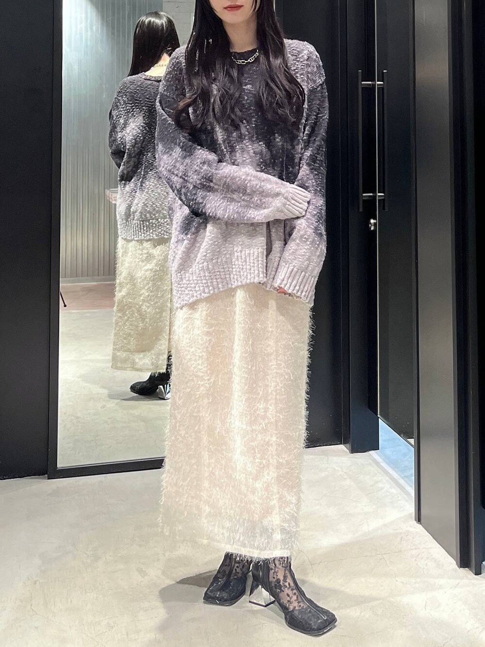 ブラック系のブーツ、ホワイト系のスカート、ブラック系のニット/セーターを着用したレディースの冬コーディネートの4枚目の写真