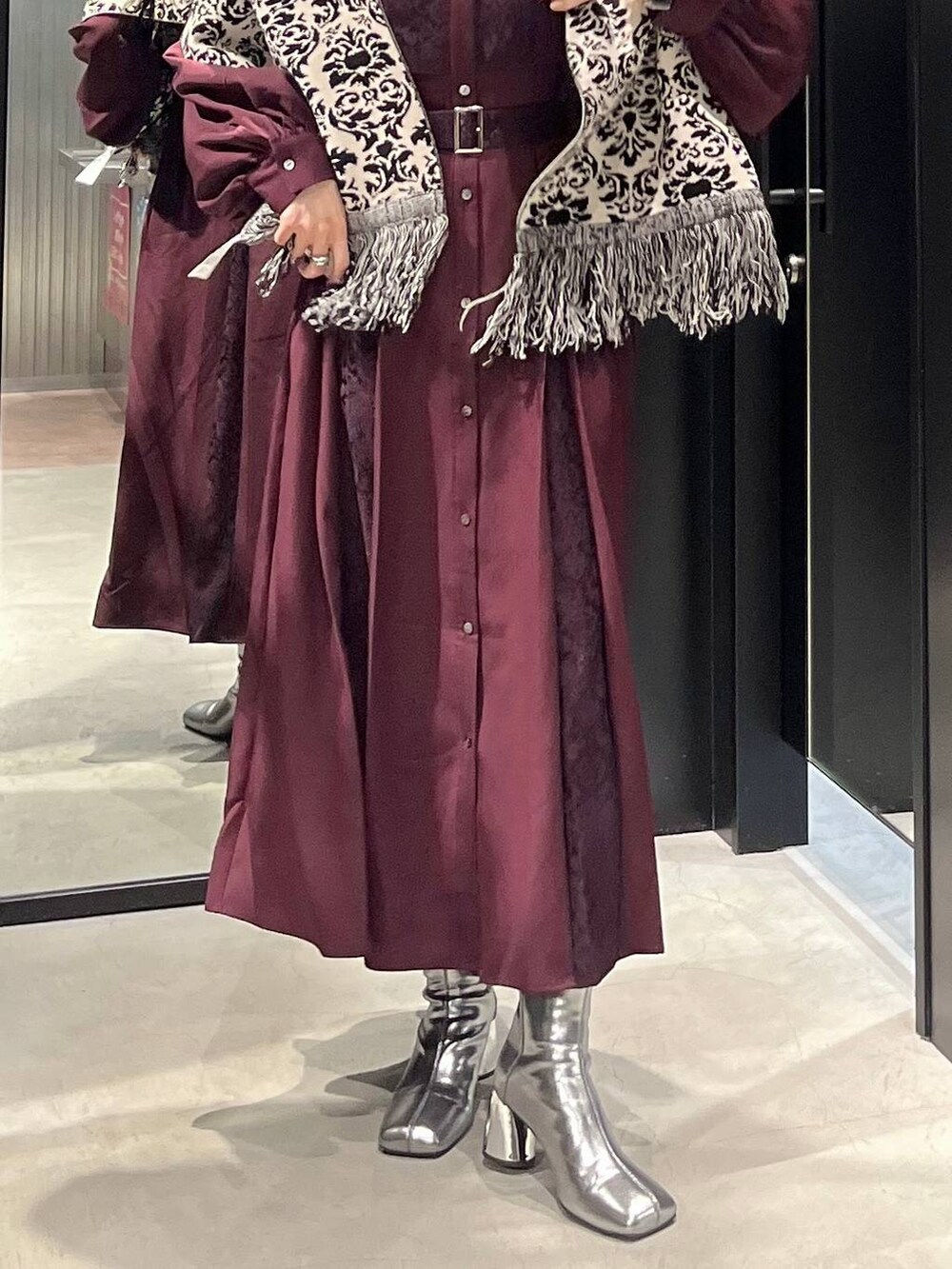 シルバー系のブーツ、レッド系のワンピース、ブラック系のマフラーを着用したレディースの秋コーディネートの3枚目の写真