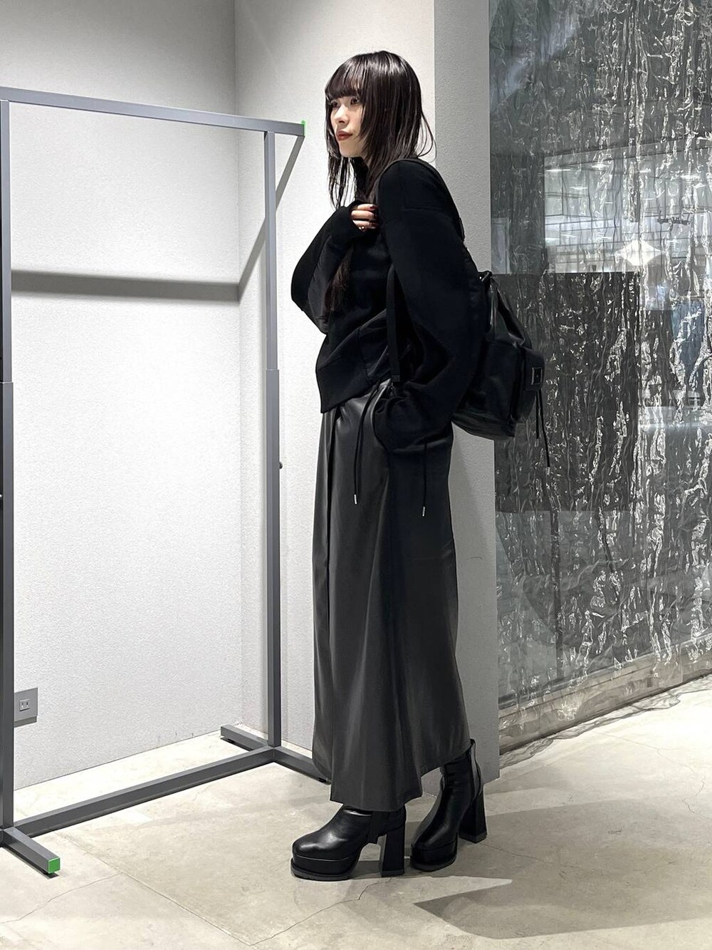 ブラック系のバックパック/リュック、ブラック系のスカート、ブラック系のブーツを着用したレディースの秋コーディネートの3枚目の写真