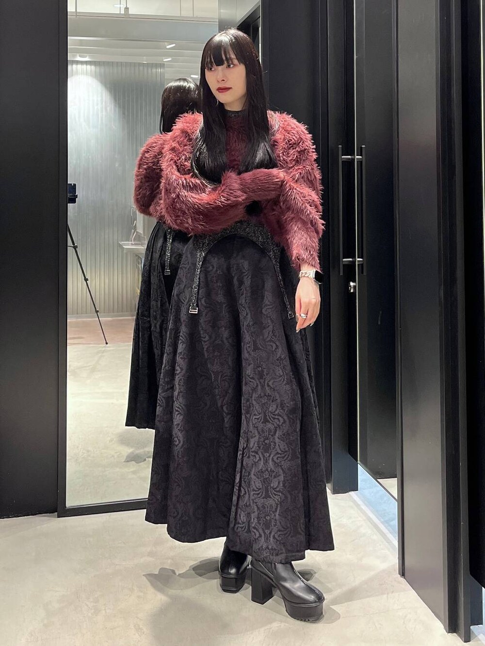 レッド系のニット/セーター、ブラック系のブーツ、ブラック系のニット/セーターを着用したレディースの秋コーディネートの3枚目の写真