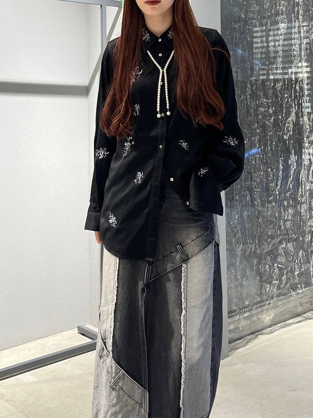 ブラック系のデニムスカート、ブラック系のシャツ/ブラウス、ブラック系のブーツを着用したレディースの秋コーディネートの2枚目の写真