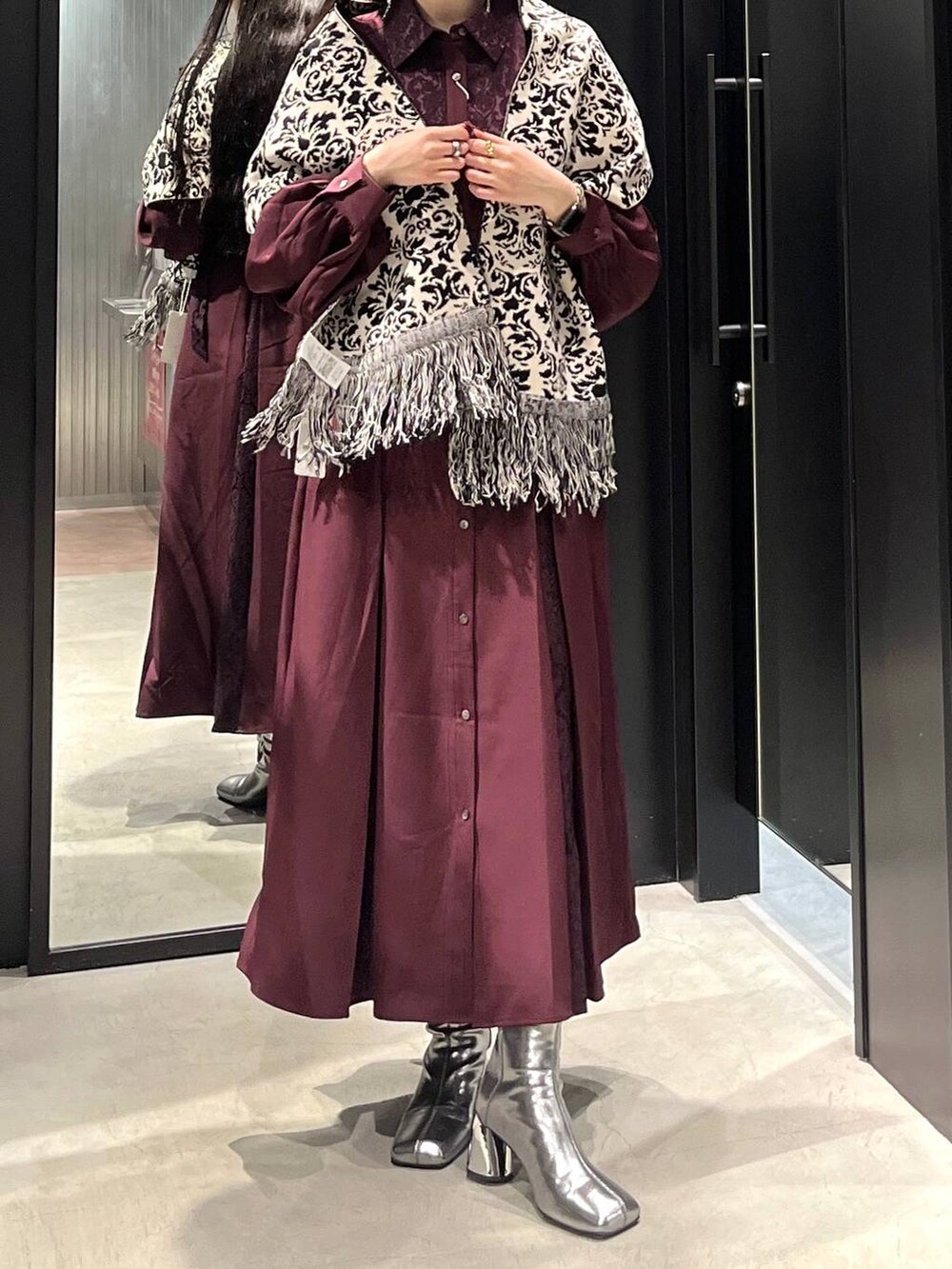 シルバー系のブーツ、レッド系のワンピース、ブラック系のマフラーを着用したレディースの秋コーディネートの2枚目の写真