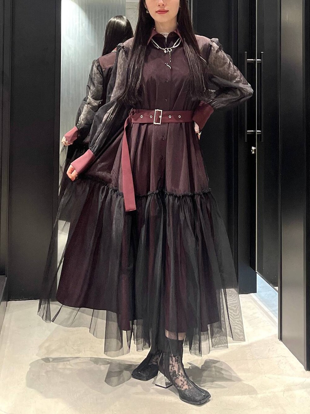 ブラック系のブーツ、レッド系のワンピース、シルバー系のネックレスを着用したレディースの春コーディネートの2枚目の写真